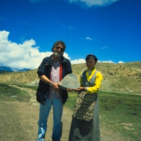 ROADSIDE PRAYER. At the end of a day spent surveying the Yangbajain graben, Cornell geophysicist Larry Brown and a young Tibetan woman display a rock with a Buddhist prayer inscribed on it, found along the road about 100 km. west of Lhasa. Grabens are sunken blocks of the Earth's crust.