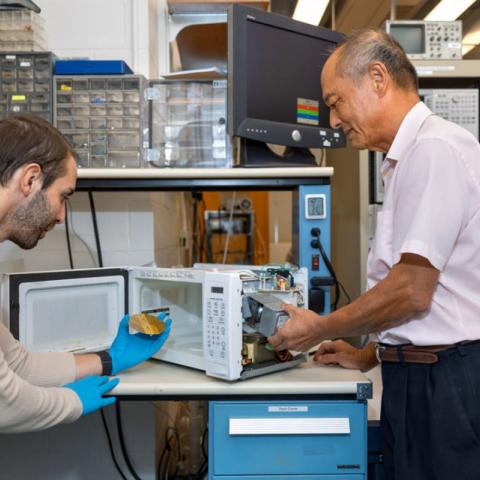 ames Hwang, research professor in the Department of Materials Science and Engineering, right, at his modified microwave with Gianluca Fabi holding a semiconductor at left.